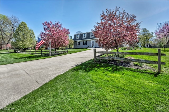 view of property hidden behind natural elements featuring fence and a front yard