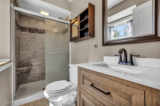 full bathroom with vanity, a shower stall, and toilet