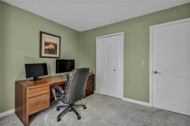 carpeted office with baseboards and a textured ceiling