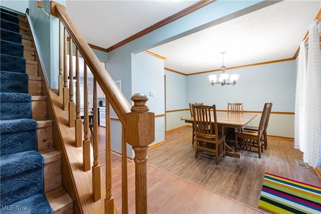dining area featuring baseboards, ornamental molding, wood finished floors, and a chandelier
