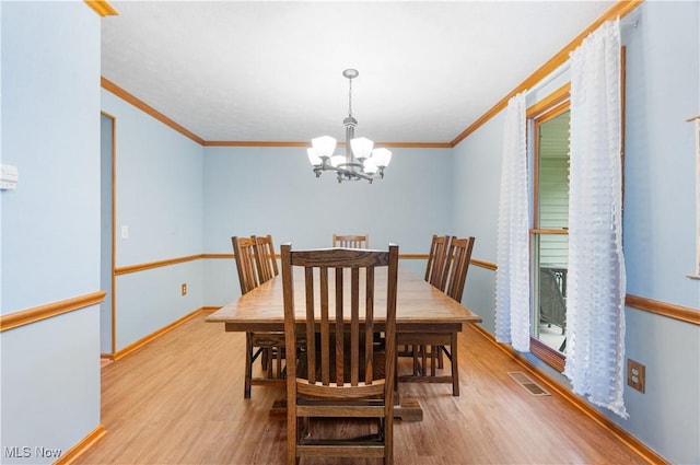 dining room featuring visible vents, crown molding, wood finished floors, baseboards, and a notable chandelier