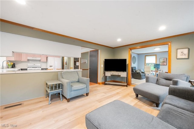 living area with crown molding, recessed lighting, light wood-type flooring, and visible vents