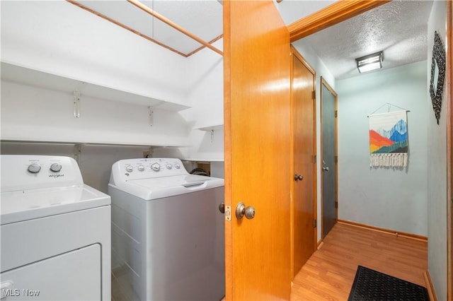 washroom featuring laundry area, baseboards, wood finished floors, and washing machine and clothes dryer