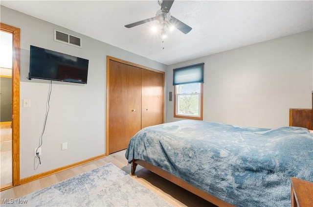 bedroom featuring baseboards, ceiling fan, light wood-style flooring, and visible vents