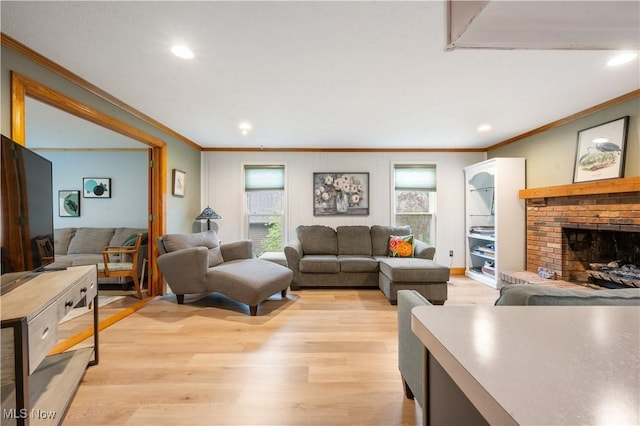 living room featuring crown molding, recessed lighting, a brick fireplace, and light wood-type flooring