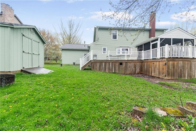 back of property featuring a storage unit, a sunroom, a deck, an outdoor structure, and a yard