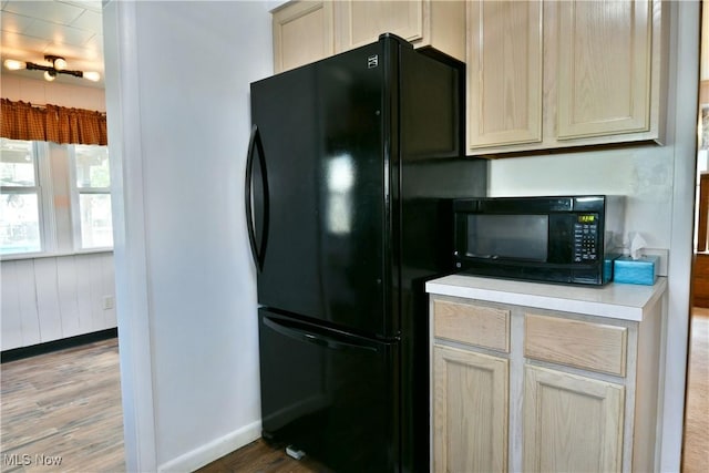 kitchen with light countertops, baseboards, wood finished floors, and black appliances
