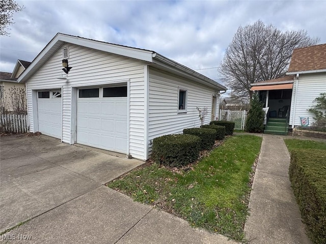 exterior space featuring a garage, fence, and an outbuilding
