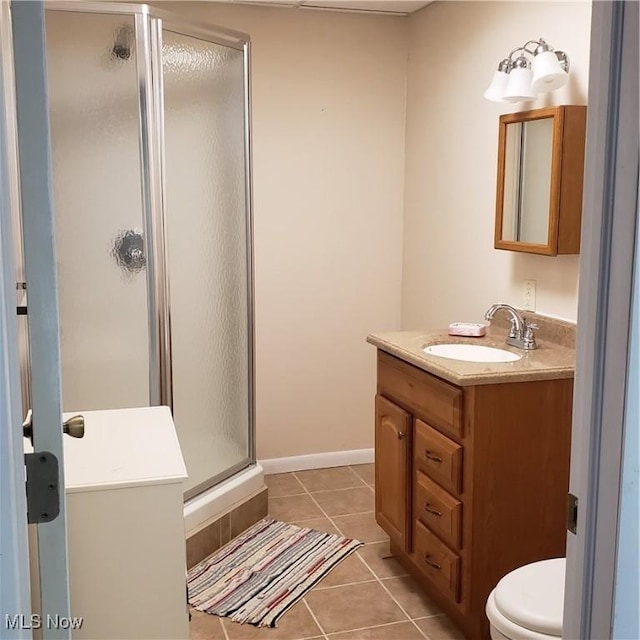 full bathroom featuring a shower stall, vanity, tile patterned floors, baseboards, and toilet