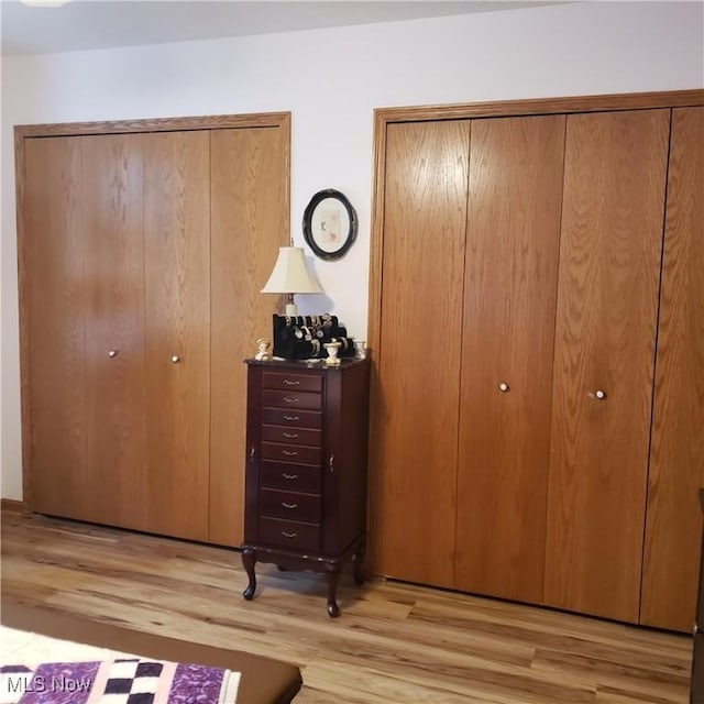 bedroom with light wood-style floors and two closets
