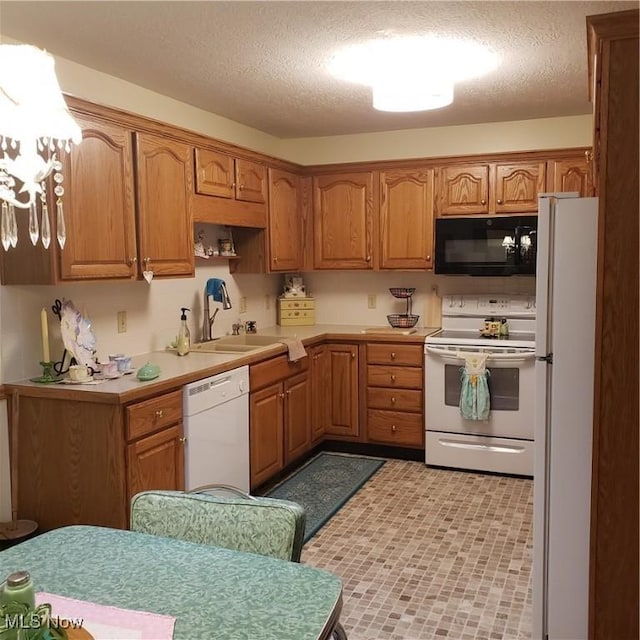kitchen with white appliances, brown cabinetry, a sink, and light countertops