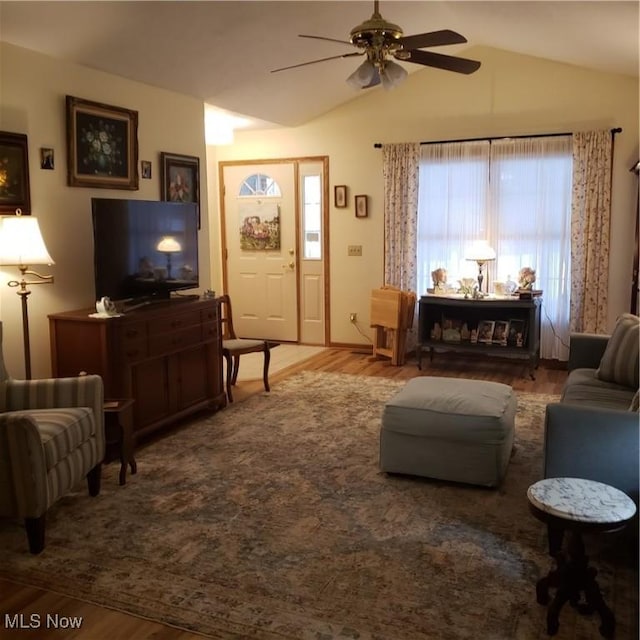 living area with ceiling fan, vaulted ceiling, and wood finished floors