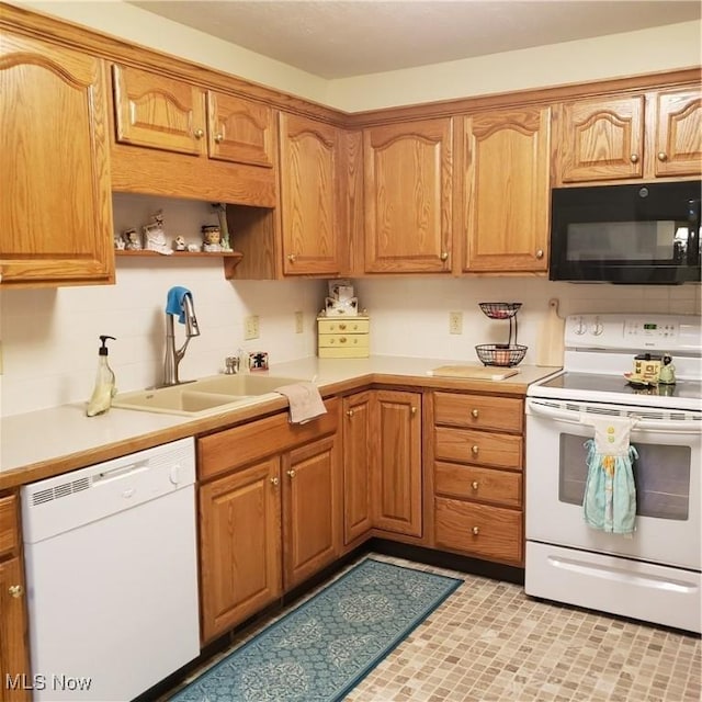 kitchen featuring white appliances, brown cabinetry, a sink, and light countertops