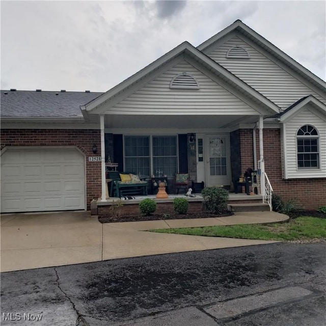 view of front of property with a porch, a garage, driveway, and brick siding