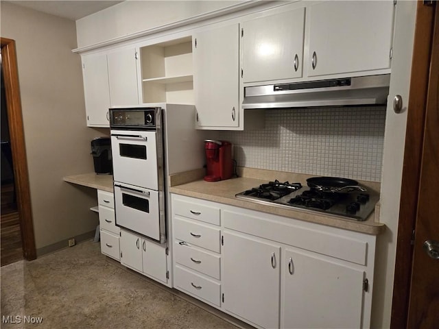 kitchen with double oven, light countertops, under cabinet range hood, tasteful backsplash, and stainless steel gas stovetop
