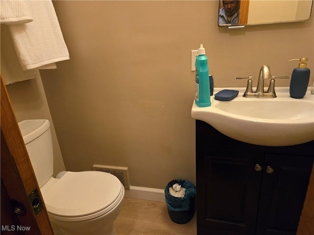 half bathroom featuring visible vents, tile patterned flooring, vanity, toilet, and baseboards