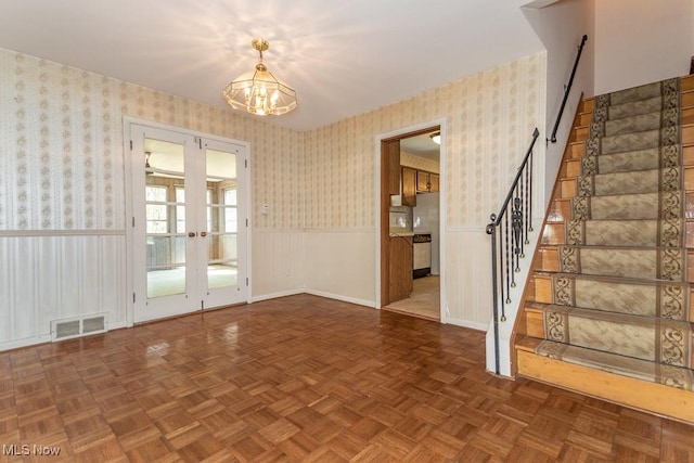 interior space featuring stairway, wainscoting, a notable chandelier, and visible vents