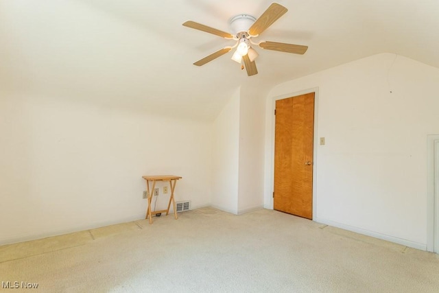 spare room featuring carpet floors, a ceiling fan, visible vents, and lofted ceiling