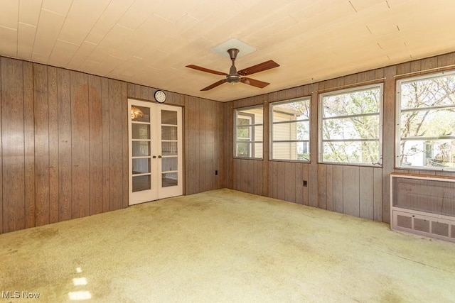 interior space with carpet floors, wooden walls, french doors, and a wealth of natural light