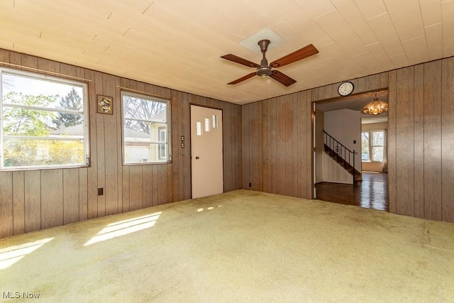 interior space featuring stairway, ceiling fan, carpet flooring, and wood walls