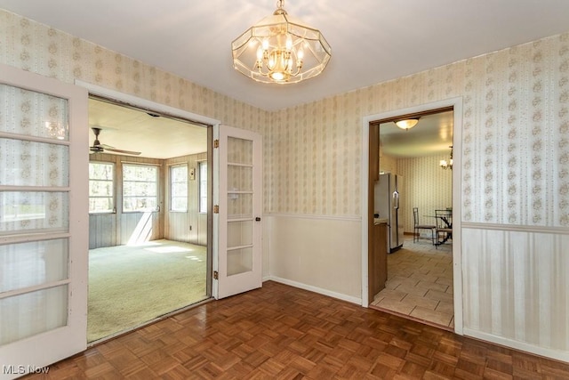 spare room with wallpapered walls and a chandelier