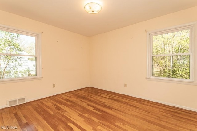 empty room with baseboards, light wood finished floors, and visible vents