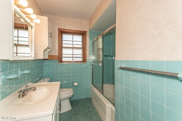 bathroom with tile walls, vanity, toilet, and a wealth of natural light