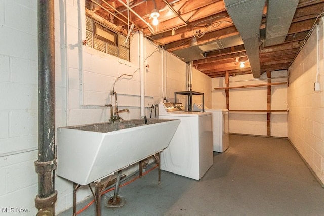 washroom with washing machine and clothes dryer, concrete block wall, laundry area, and a sink