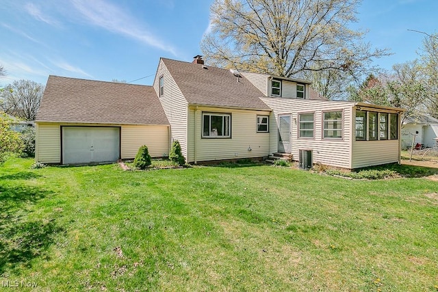 rear view of house featuring a lawn, a chimney, a sunroom, and roof with shingles
