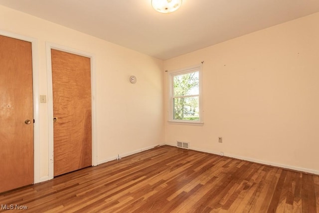 unfurnished bedroom with baseboards, visible vents, and wood finished floors