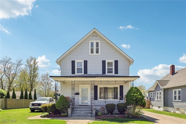 american foursquare style home with a front lawn, fence, and covered porch