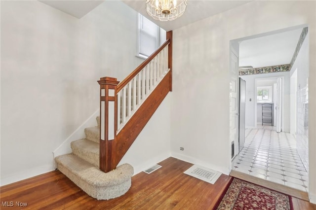 stairs featuring baseboards, a notable chandelier, and visible vents