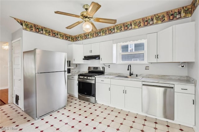 kitchen with light floors, white cabinetry, under cabinet range hood, a sink, and appliances with stainless steel finishes