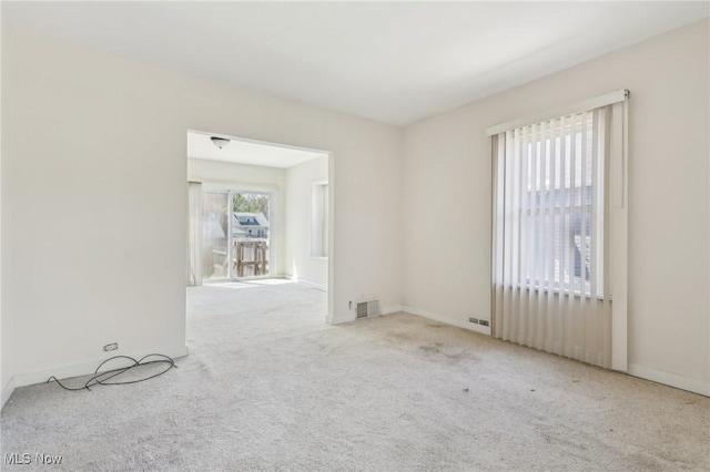 carpeted empty room featuring baseboards and visible vents