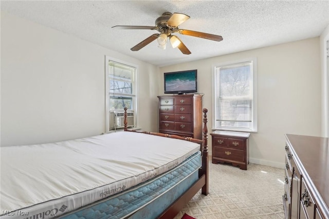 bedroom featuring light colored carpet, a textured ceiling, ceiling fan, and baseboards