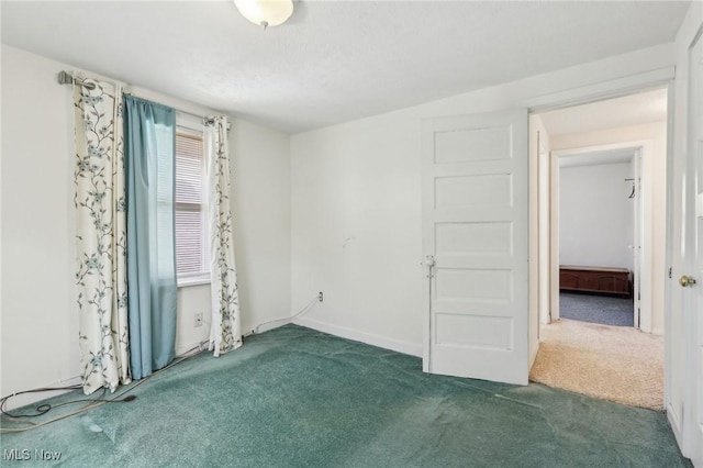 carpeted empty room featuring baseboards