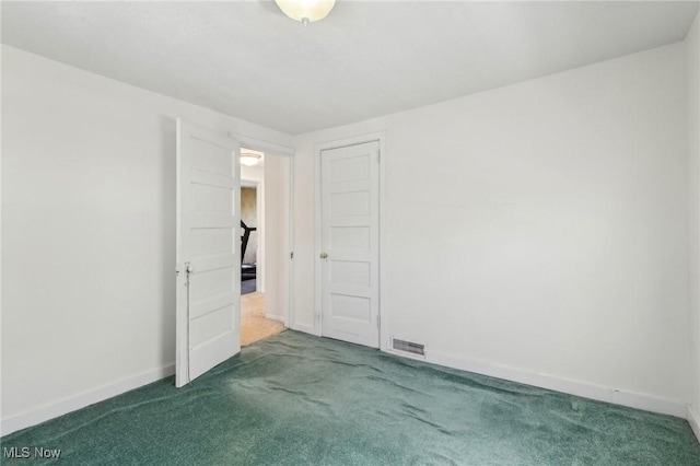 unfurnished bedroom with baseboards, dark colored carpet, and visible vents