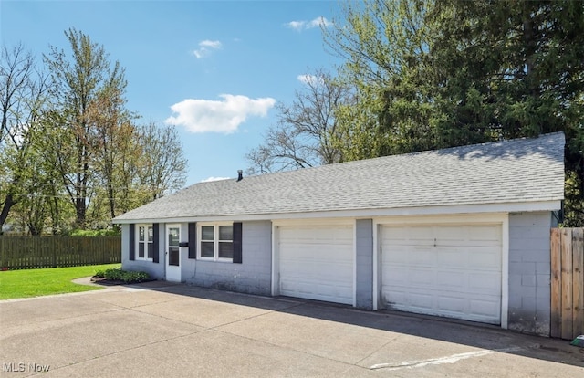 single story home featuring concrete block siding, roof with shingles, fence, and a detached garage