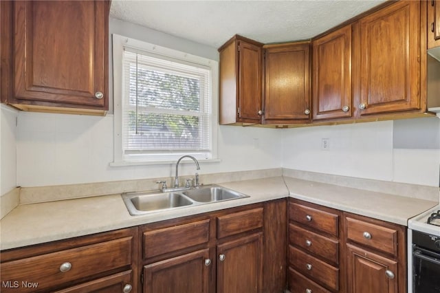 kitchen with a sink, light countertops, brown cabinets, and electric range