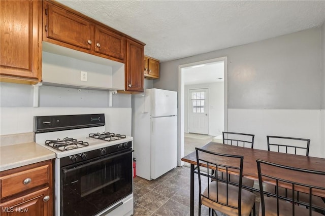kitchen with brown cabinetry, light countertops, and white appliances
