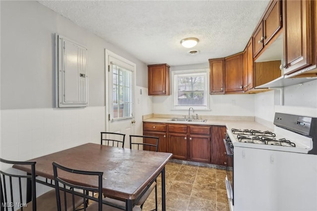 kitchen with a textured ceiling, a sink, gas range gas stove, and electric panel
