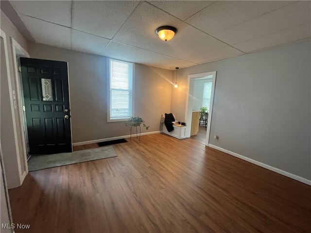 interior space with a paneled ceiling, baseboards, and wood finished floors