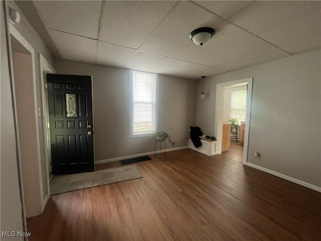 foyer featuring baseboards, a drop ceiling, and wood finished floors