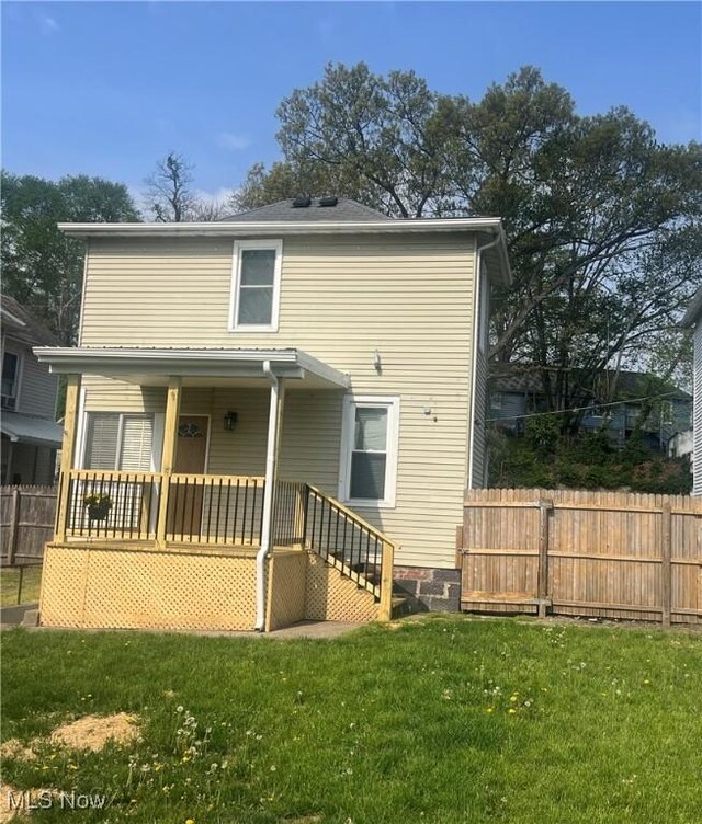 rear view of property with fence, a lawn, and a porch