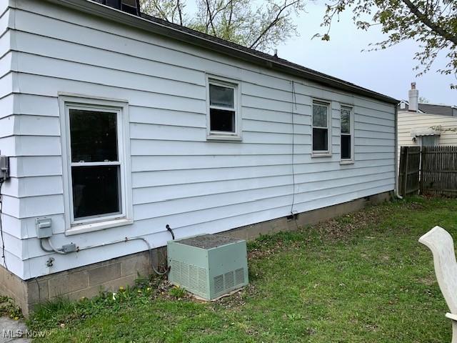 view of side of property featuring a yard, fence, and central AC unit
