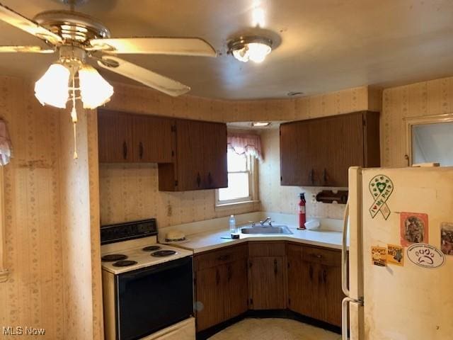 kitchen with freestanding refrigerator, electric range, a sink, and light countertops
