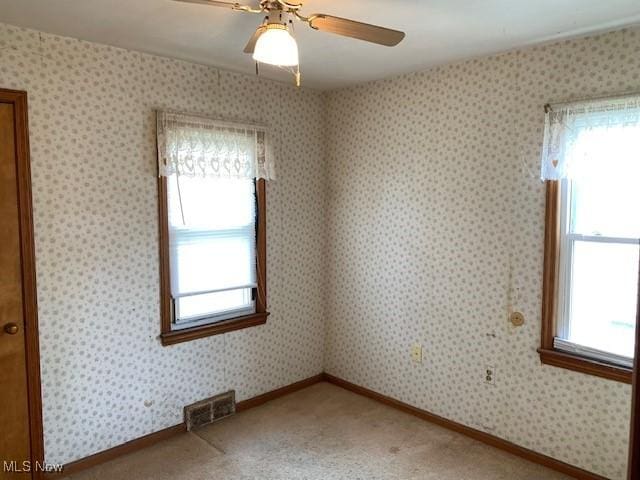 empty room featuring light colored carpet, ceiling fan, and visible vents