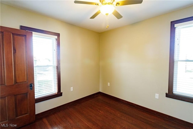 spare room with baseboards, a ceiling fan, and dark wood-style flooring