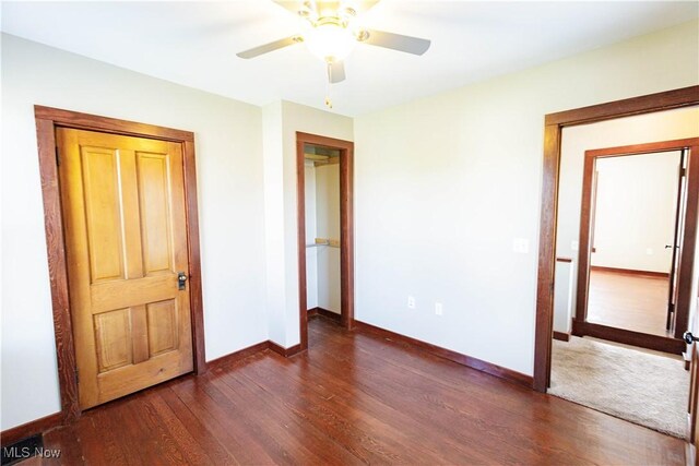 unfurnished bedroom featuring baseboards, dark wood-style flooring, and ceiling fan