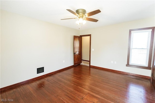 spare room with baseboards, ceiling fan, dark wood-style floors, and visible vents